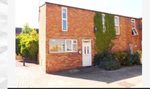 a brick building with a white door and ivy at Vetrelax Basildon Newly refurbished 3bed House in Basildon