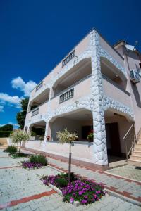 a white building with flowers in front of it at Apartments Ruzica in Pinezici