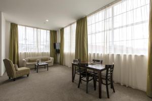 uma sala de estar com uma mesa, cadeiras e janelas em Quest Hamilton Serviced Apartments em Hamilton