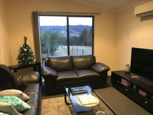 a living room with a leather couch and a large window at Yeoy's Cabin in Tallarook