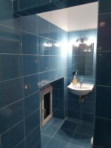 Un baño con azulejos azules, lavabo y espejo. en Vivaldi Studios, en Cluj-Napoca