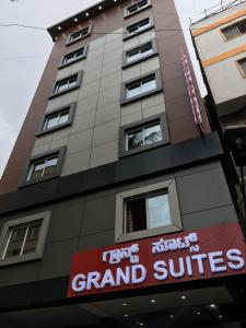 a tall building with a sign for a grand suites at Hotel Grand Suites in Bangalore