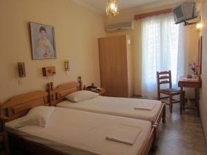 a bedroom with two beds and a table and a chair at Sandalis Hotel in Pythagoreio