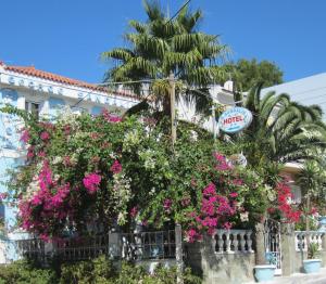 ein Gebäude mit rosa Blumen und einer Palme in der Unterkunft Sandalis Hotel in Pythagoreio