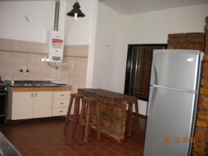 Una cocina con nevera y una mesa con taburetes. en Chalet Carlos Paz, en Villa Carlos Paz 20 fotos más