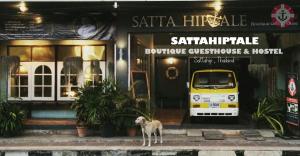 a dog standing in front of a shop with a van in front at Sattahiptale Boutique Guesthouse & Hostel in Sattahip