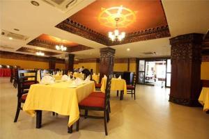 una sala da pranzo con tavoli e sedie gialli e un lampadario di Hotel Tibet International a Kathmandu