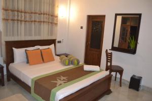 a bedroom with a bed with pillows and a chair at Nice To Meet Home Stay in Habarana