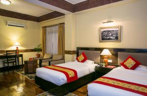 
a hotel room with two beds and two lamps at Hotel Tibet International in Kathmandu
