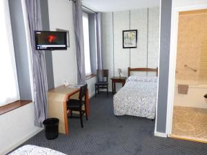 Habitación de hotel con cama, escritorio y TV. en Hôtel Restaurant "Le Relais", en Courtenay