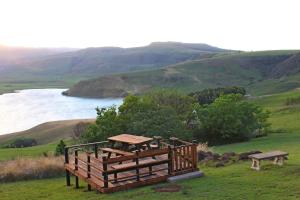 un banco y una mesa de picnic en una colina con un lago en Treks, Trips and Trails, en Champagne Valley