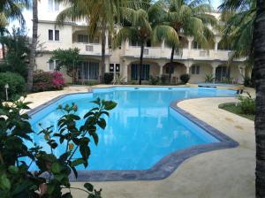 a swimming pool in front of a building with palm trees at Le Palmier C10 in Flic-en-Flac