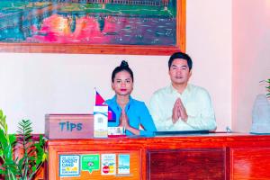 a man and a woman standing behind a desk with a picture of them at BayStone Resort in Siem Reap