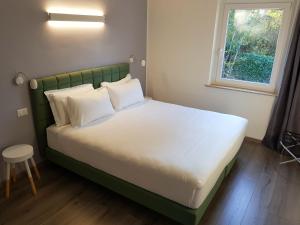 een bed met witte kussens in een kamer met een raam bij Hotel Aurora Duino in Duino