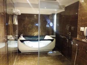 a bath tub in a bathroom with a glass wall at Hotel Oxina Lygon in Tiruchchirāppalli