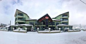 a large building with snow on the ground in front of it at Hotel Villa Palace in Bakuriani