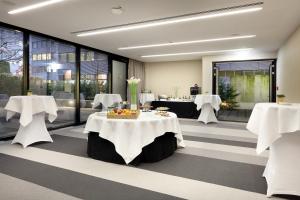 a restaurant with white tables and chairs and windows at Eurostars Book Hotel in Munich