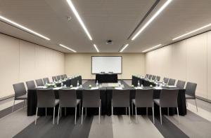 a conference room with a table and chairs and a screen at Eurostars Book Hotel in Munich