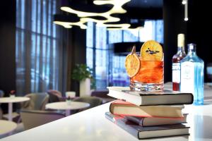 a stack of books on a table with a drink at Eurostars Book Hotel in Munich