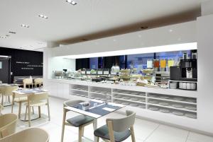 a restaurant with tables and chairs and a kitchen at Eurostars Book Hotel in Munich