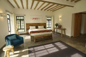 a bedroom with a bed and a blue chair at Arusha Villa Karamu Coffee Estate in Usa River