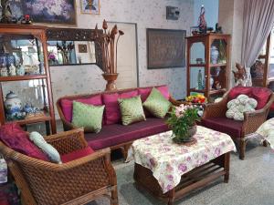 uma sala de estar com um sofá roxo, cadeiras e uma mesa em Wiang Inn Mansion em Chiang Mai