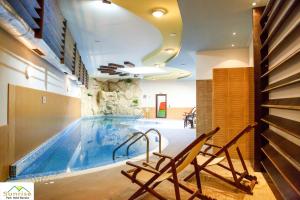 una piscina con 2 sillas frente a ella en Sunrise Park Complex - Free Wellness, en Bansko