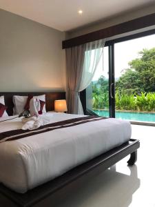 a bedroom with a large bed and a large window at Amarina Green in Lamai