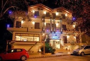 a building with a red car parked in front of it at Hotel Prigipikon Suites and sofites in Loutra Ipatis