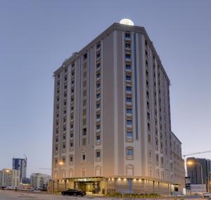 un gran edificio blanco con un reloj encima en Ramee Rose Hotel, en Manama