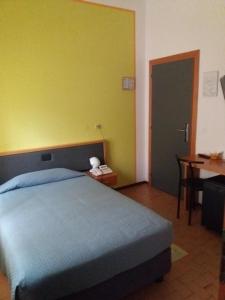 a bedroom with a bed and a yellow wall at Hotel Bermuda in Marina di Ravenna