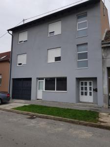 a gray house with white windows and a driveway at Apartman Lena in Osijek
