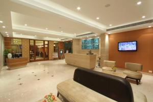 a lobby with a couch and a tv on a wall at Hotel Riverview in Ahmedabad