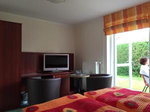 a room with a bed and a television and a table at Gasthaus & Pension "Zur Schaabe" in Glowe