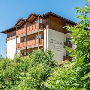 un edificio de apartamentos con árboles en el primer plano en Naturhotel Waldheim, en Anterivo