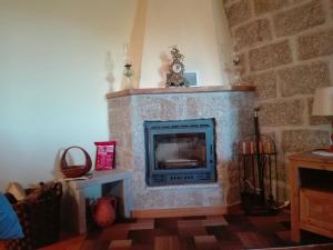 a living room with a stone fireplace with a clock at Casa d'Avó Serra da Estrela in Seia