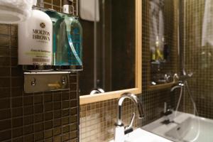 a bathroom with a bottle of alcohol on a mirror at Mimi's Hotel Soho in London