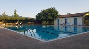 a swimming pool in front of a house at Campastrello Sport Hotel Residence in Castagneto Carducci