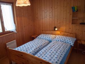 ein Schlafzimmer mit einem Bett in einem Holzzimmer in der Unterkunft Chalet Silberdistel in Rosswald