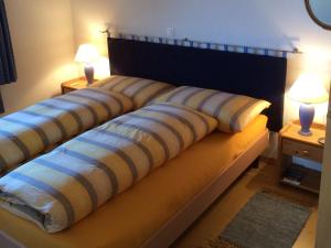 Una cama con dos almohadas y dos lámparas. en Chalet Bergkristall, en Rosswald