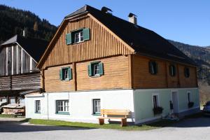 a house with a wooden roof with a bench in front at Ferienwohnung Schaupphof in Donnersbachwald