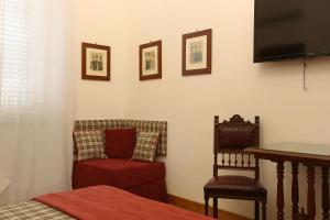 a bedroom with a bed and a chair and a television at Houspitality Caesar Bed & Breakfast in Rome