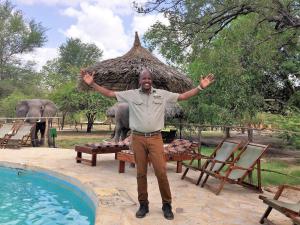 Un uomo in piedi di fronte a una piscina con le mani in alto di Africa Safari Selous Nyerere national park a Nyakisiku