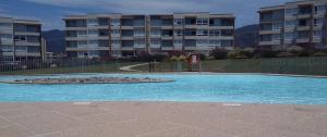 a swimming pool in front of a apartment building at Lomas de Papudo Departamento in Papudo