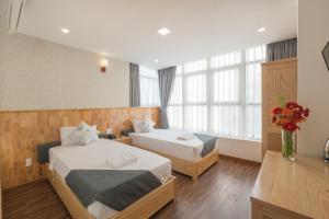 a hotel room with two beds and a vase of flowers at Beauty House in Ho Chi Minh City