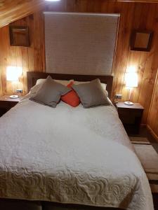 1 cama grande con 2 lámparas en 2 mesas en Cabañas Emma, en Osorno