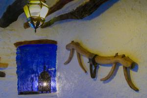 a wall with a pair of horns on a wall with a blue window at La Casa de la Bombilla Verde in Trevélez