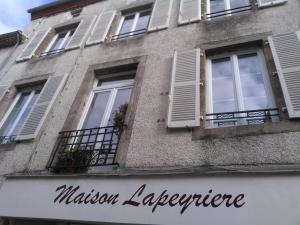 a building with white windows and a sign on it at Maison Lapeyriere in Le Dorat
