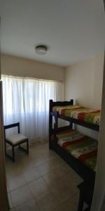 een slaapkamer met 2 stapelbedden en een stoel bij Departamento del Mar in Mar del Plata