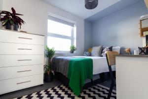 a bedroom with a bed with a green blanket on it at Roseland House in Falmouth